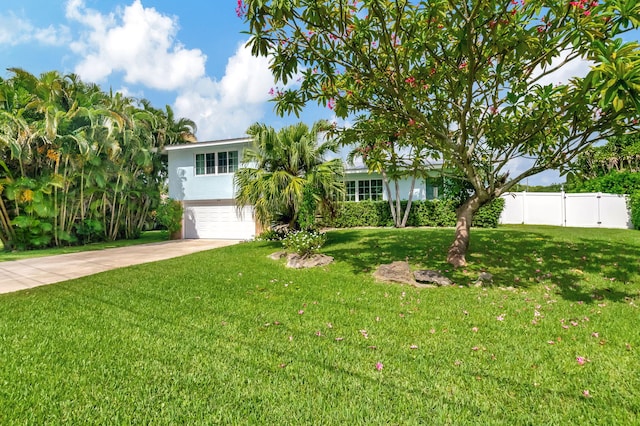 view of front of home with a front yard, concrete driveway, stucco siding, fence, and an attached garage