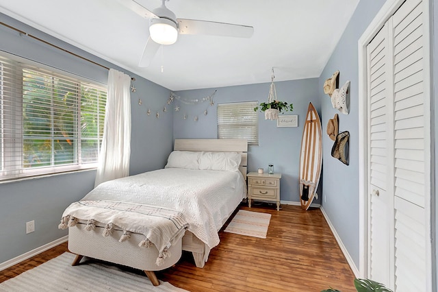 bedroom with baseboards, wood finished floors, a closet, and a ceiling fan