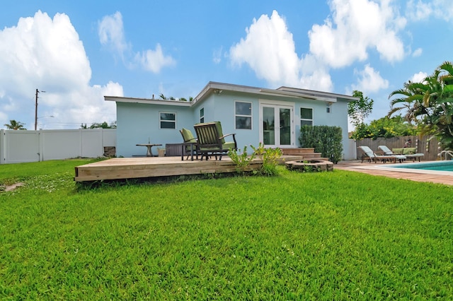back of house with a wooden deck, french doors, a fenced backyard, a fenced in pool, and a yard