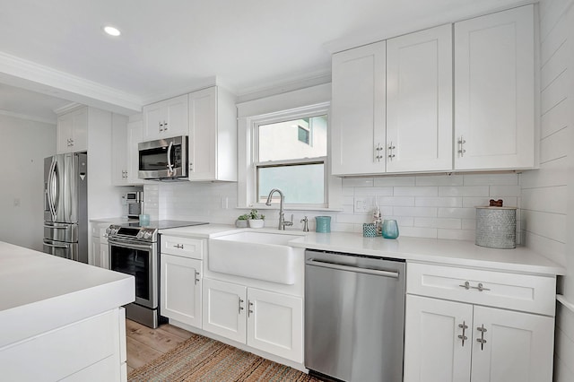 kitchen with appliances with stainless steel finishes, light hardwood / wood-style flooring, backsplash, and white cabinets