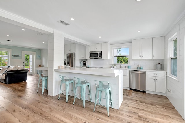 kitchen featuring a breakfast bar, light countertops, light wood-style flooring, and stainless steel appliances