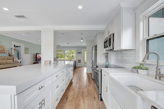 kitchen with light hardwood / wood-style floors, backsplash, stainless steel appliances, and white cabinetry