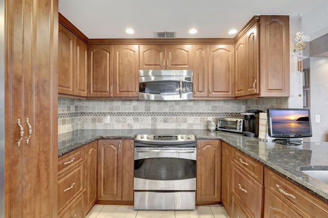 kitchen featuring light tile patterned floors, stainless steel appliances, backsplash, and dark stone countertops