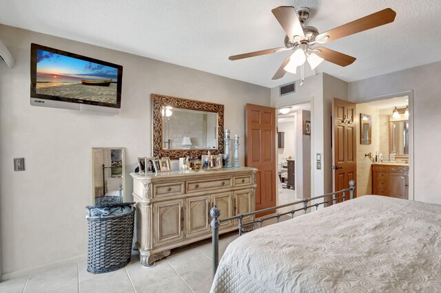 tiled bedroom featuring a textured ceiling, ceiling fan, and ensuite bath