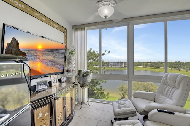 sunroom with ceiling fan and a water view