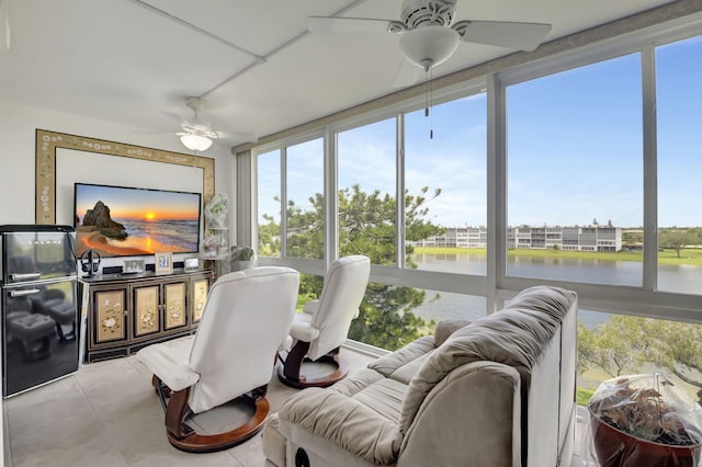 sunroom featuring ceiling fan and a water view