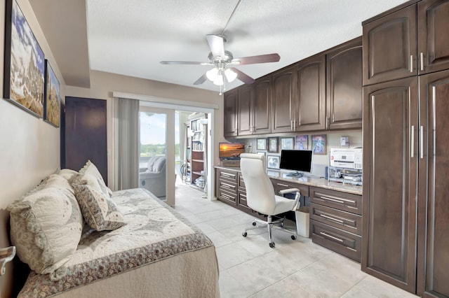 office space with a textured ceiling, ceiling fan, built in desk, and light tile patterned floors