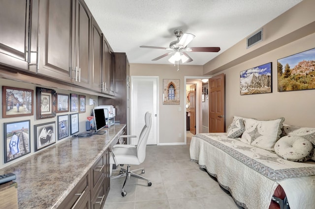 bedroom featuring light tile patterned floors, ceiling fan, ensuite bathroom, built in desk, and a textured ceiling