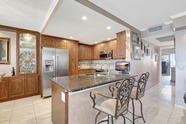 kitchen with appliances with stainless steel finishes, dark stone counters, tasteful backsplash, sink, and crown molding