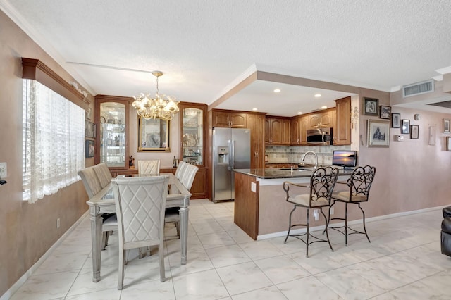 kitchen featuring dark stone counters, a chandelier, appliances with stainless steel finishes, light tile patterned floors, and backsplash