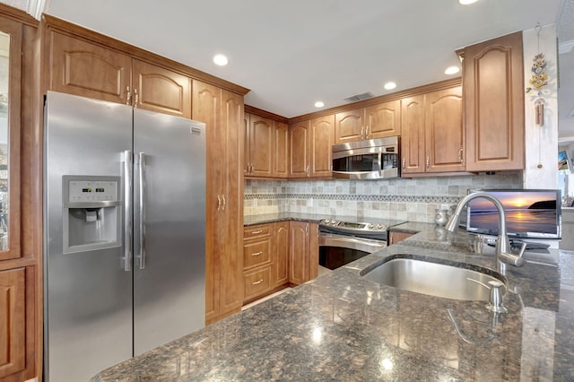 kitchen with sink, decorative backsplash, dark stone counters, and stainless steel appliances