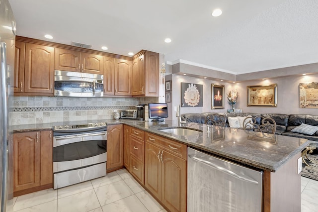 kitchen with sink, appliances with stainless steel finishes, backsplash, kitchen peninsula, and dark stone counters