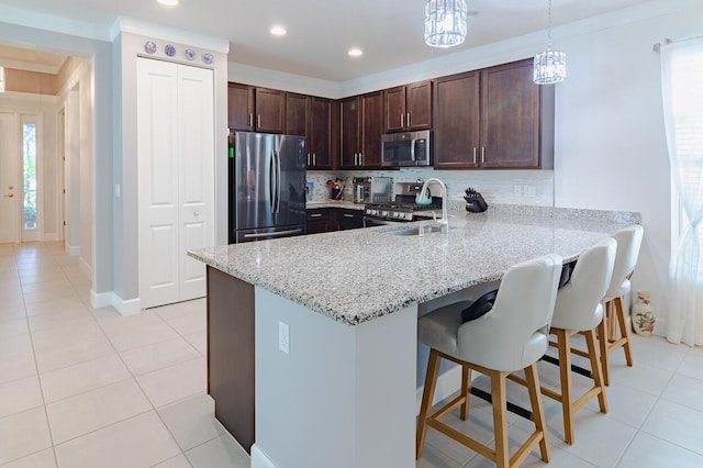 kitchen with a peninsula, a sink, appliances with stainless steel finishes, light stone countertops, and pendant lighting