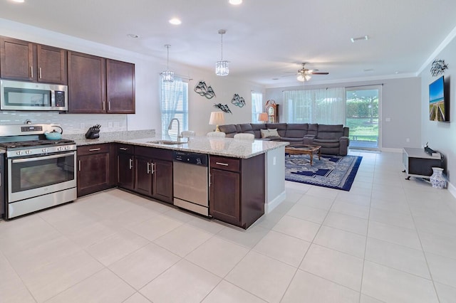 kitchen featuring pendant lighting, stainless steel appliances, open floor plan, a sink, and a peninsula