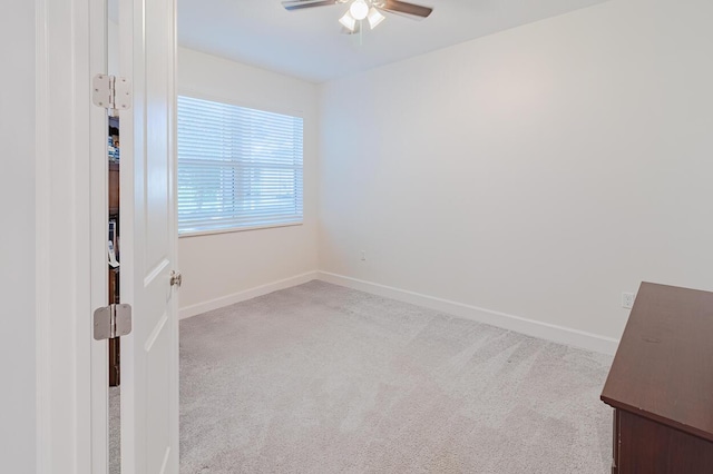 spare room featuring baseboards, ceiling fan, and light colored carpet