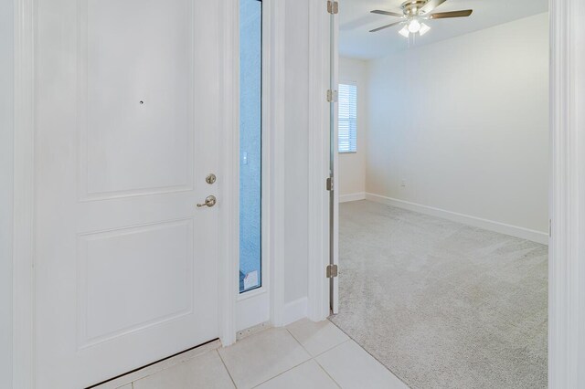 foyer entrance featuring light carpet, light tile patterned flooring, a ceiling fan, and baseboards