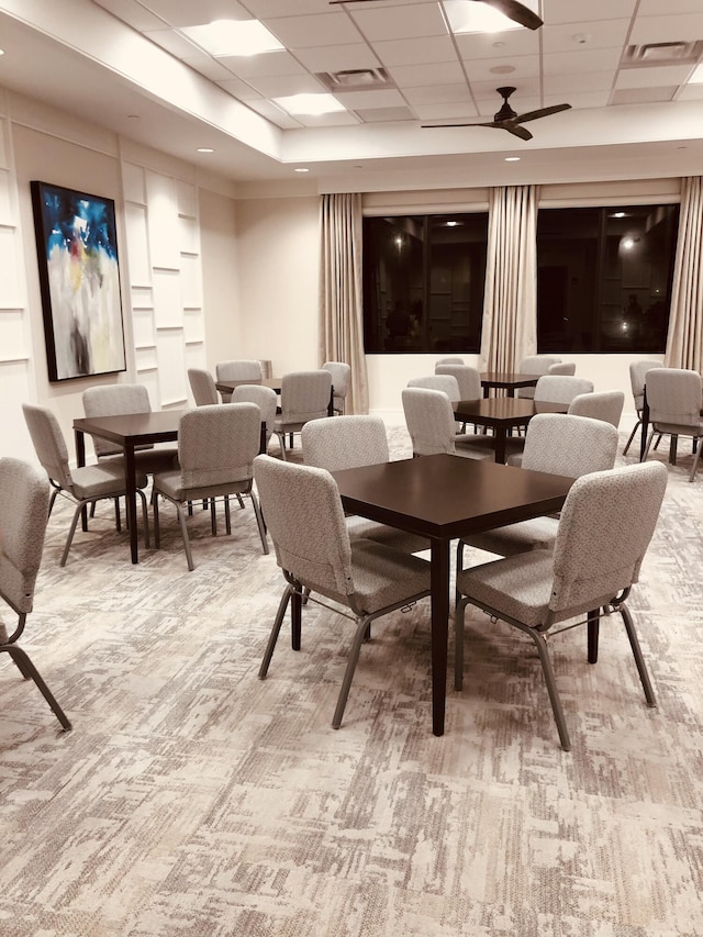 dining space featuring carpet floors, a drop ceiling, visible vents, and a ceiling fan