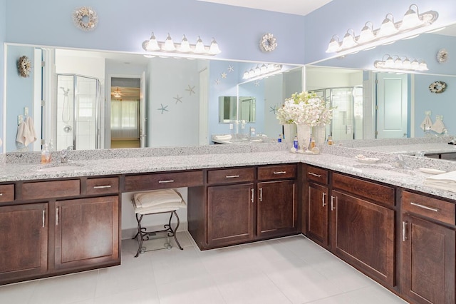 bathroom with a sink, a shower stall, and double vanity