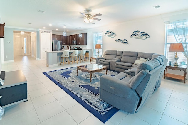 living room featuring light tile patterned floors, a ceiling fan, visible vents, and ornamental molding