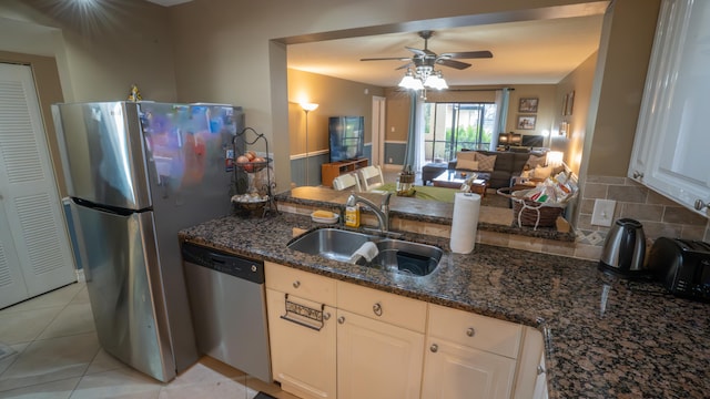 kitchen featuring dark stone countertops, white cabinets, stainless steel appliances, and sink