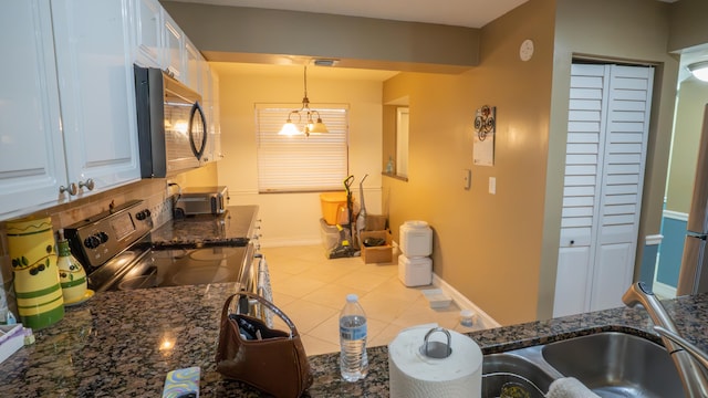 kitchen featuring pendant lighting, dark stone counters, stainless steel range with electric cooktop, white cabinets, and light tile patterned floors