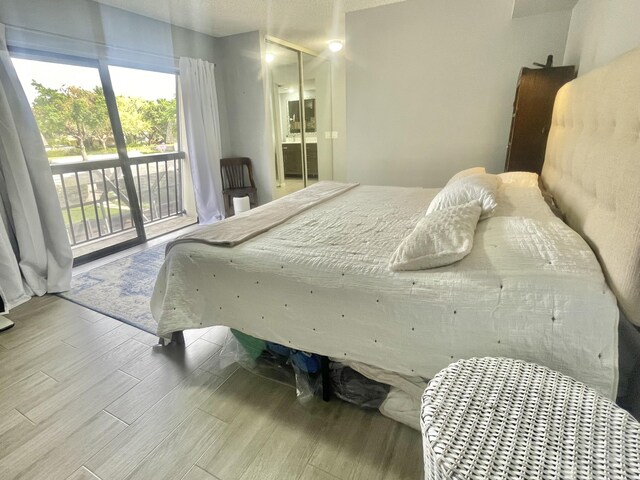 bedroom with access to exterior, wood-type flooring, and multiple windows