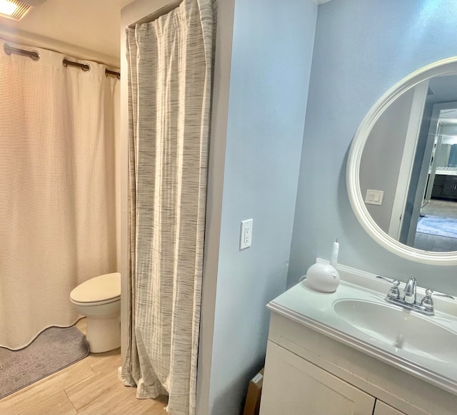 bathroom featuring vanity, toilet, wood-type flooring, and walk in shower