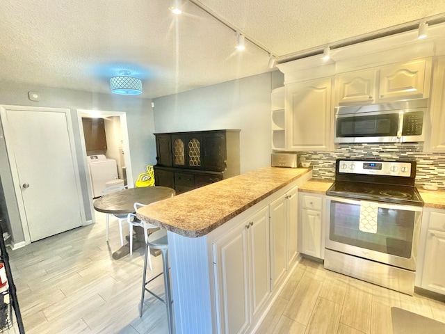 kitchen with track lighting, kitchen peninsula, stainless steel appliances, and a kitchen breakfast bar