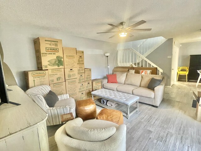 living room with a textured ceiling, ceiling fan, and wood-type flooring