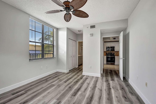 spare room featuring ceiling fan, light hardwood / wood-style floors, and a textured ceiling