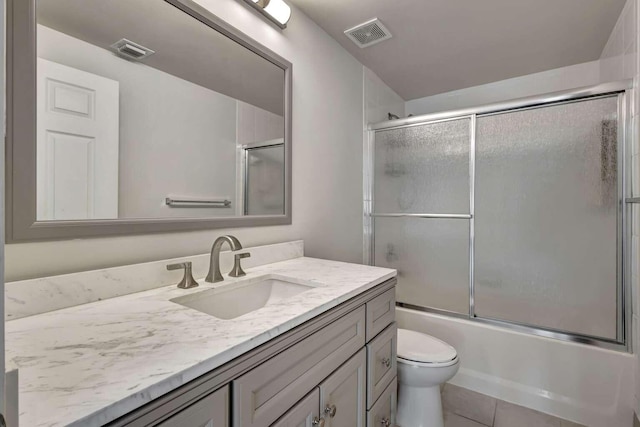 full bathroom featuring combined bath / shower with glass door, tile patterned flooring, vanity, and toilet