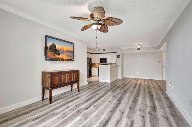 unfurnished living room with ceiling fan, light hardwood / wood-style floors, and ornamental molding