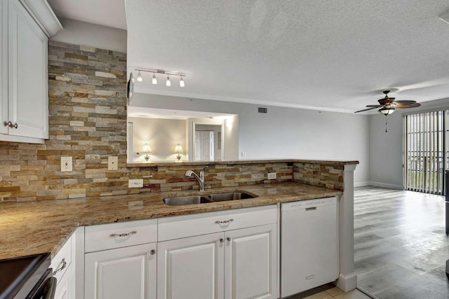 kitchen featuring sink, white dishwasher, stone countertops, track lighting, and ceiling fan