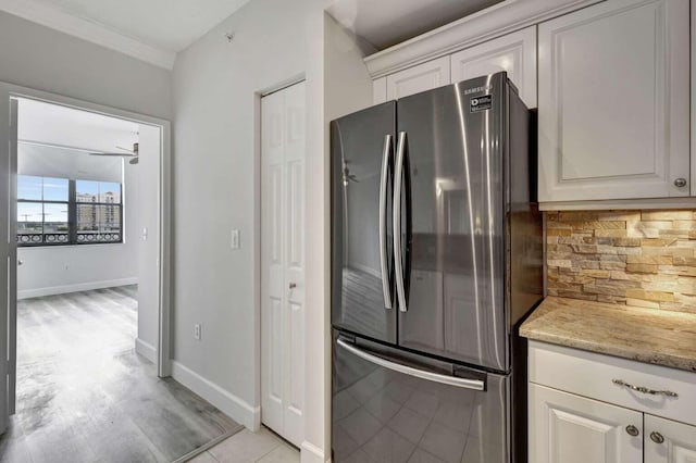 kitchen featuring backsplash, light stone counters, light hardwood / wood-style floors, white cabinetry, and stainless steel fridge