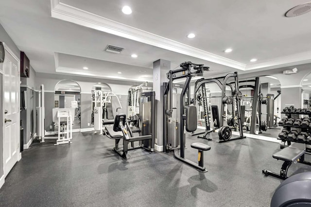 workout area featuring a tray ceiling and ornamental molding