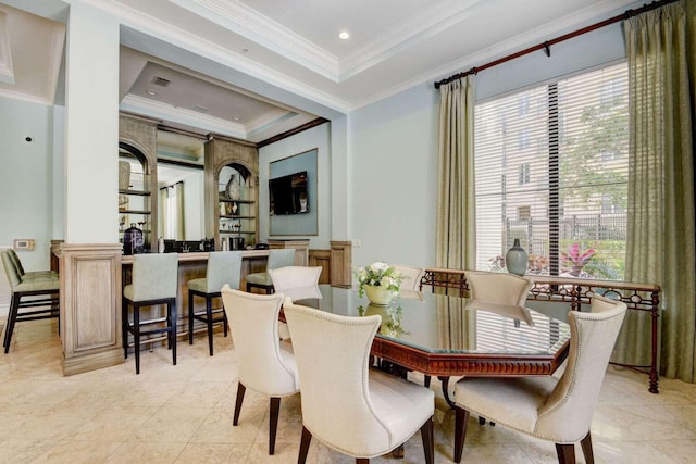 tiled dining area with a raised ceiling and crown molding