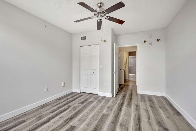 unfurnished bedroom featuring ceiling fan, hardwood / wood-style flooring, a closet, and a textured ceiling