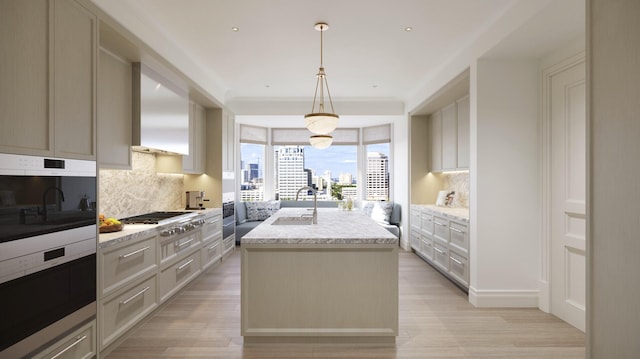 kitchen with light hardwood / wood-style flooring, backsplash, a center island with sink, and hanging light fixtures