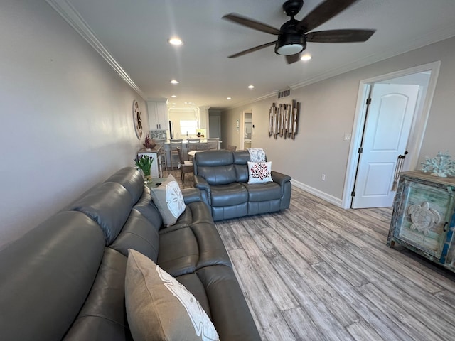 living room featuring ceiling fan, light wood-type flooring, and crown molding