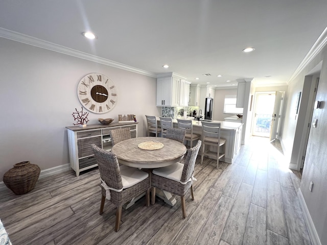 dining area with light wood-style floors, baseboards, ornamental molding, and recessed lighting