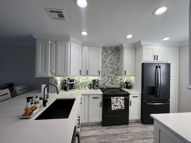 kitchen with tasteful backsplash, recessed lighting, visible vents, a sink, and black appliances