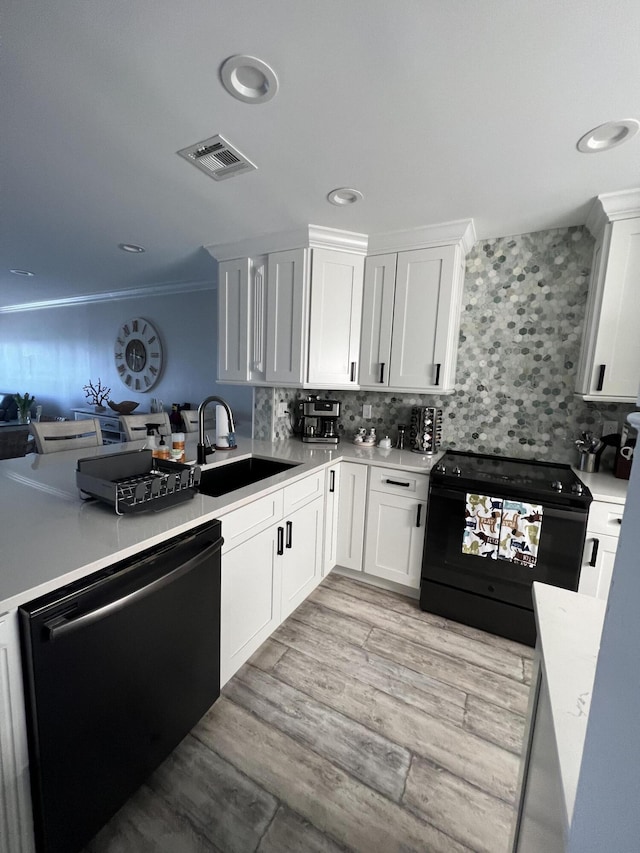 kitchen featuring dishwashing machine, black range with electric cooktop, a sink, visible vents, and decorative backsplash