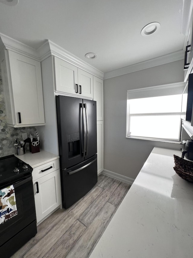 kitchen featuring black appliances, light wood-style floors, white cabinets, and crown molding