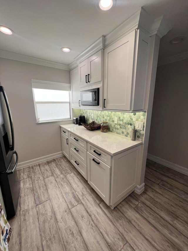 kitchen with decorative backsplash, white cabinetry, light hardwood / wood-style floors, and stainless steel appliances