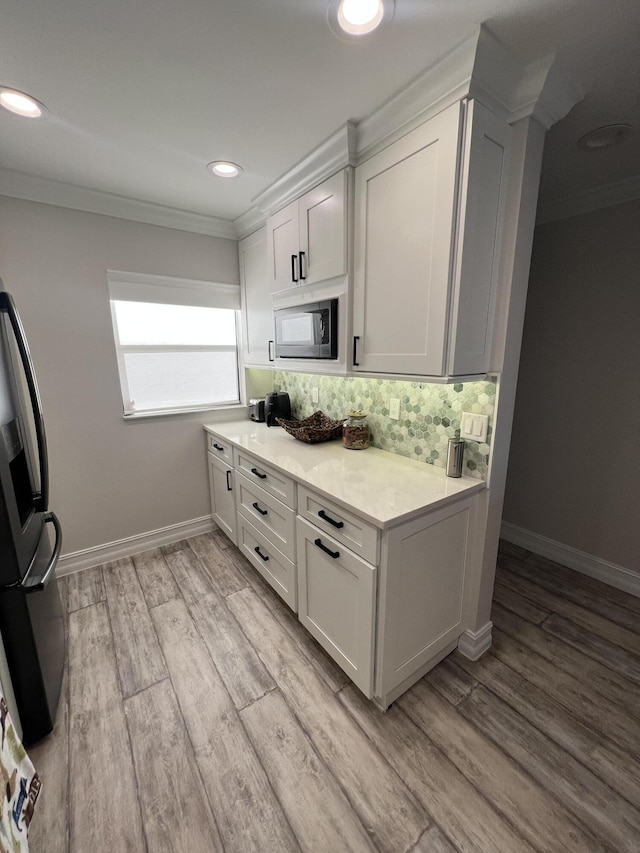 kitchen with tasteful backsplash, ornamental molding, fridge with ice dispenser, and built in microwave