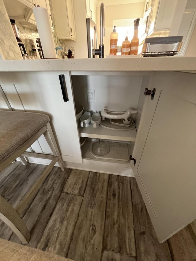 room details featuring a kitchen bar, white cabinets, wood finished floors, and light countertops