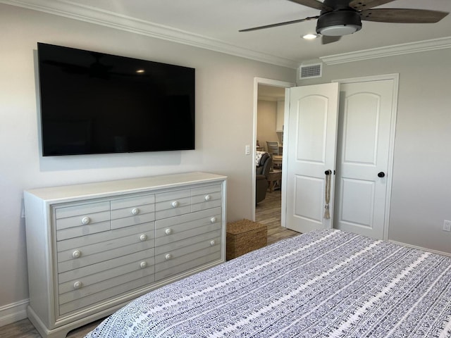 bedroom featuring light wood finished floors, baseboards, visible vents, ceiling fan, and ornamental molding