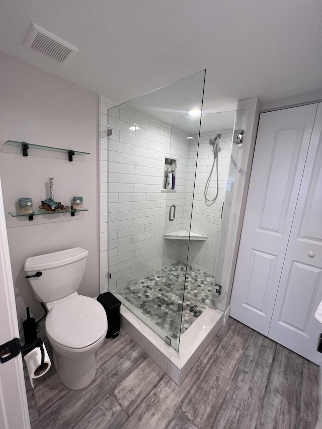 full bathroom with visible vents, a stall shower, wood finished floors, and toilet