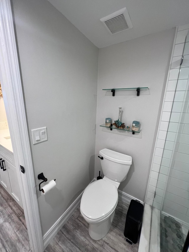 bathroom featuring toilet, hardwood / wood-style floors, vanity, and a tile shower