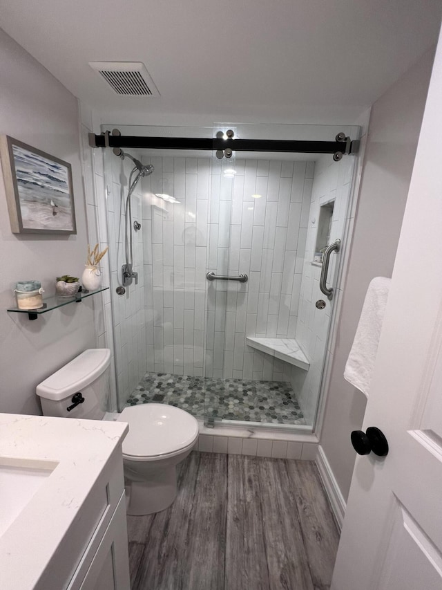 full bathroom featuring toilet, wood finished floors, vanity, visible vents, and a stall shower